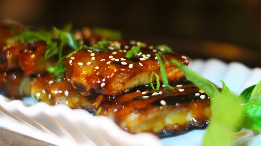 Glossy Asian-style glazed dish topped with sesame seeds and green onions at Archie's Wok in Puerto Vallarta.