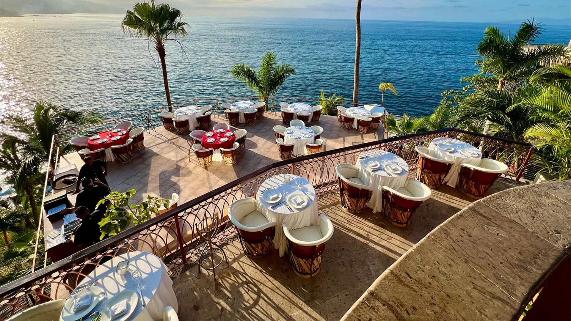 Oceanfront dining terraces at Le Kliff restaurant south of Puerto Vallarta, with elegant tables, palm trees and panoramic Banderas Bay views.