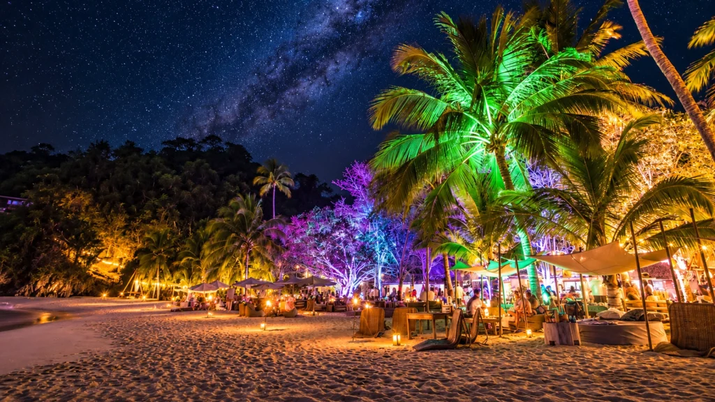 Majahuitas Beach Party at night with illuminated palm trees, beachfront lounges and a star-filled sky near Puerto Vallarta