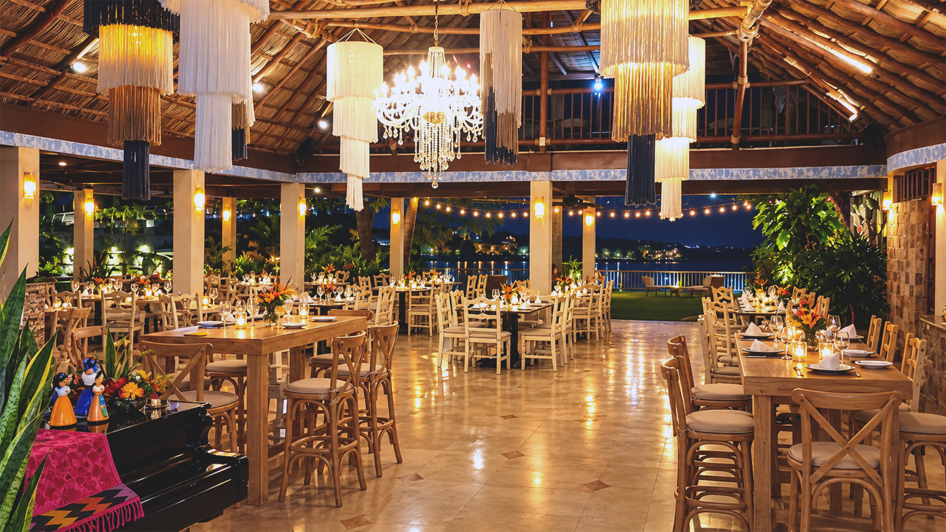 Open-air dining room at Oscar's Restaurant in Puerto Vallarta, featuring a thatched palapa roof, chandeliers and elegant wooden tables.