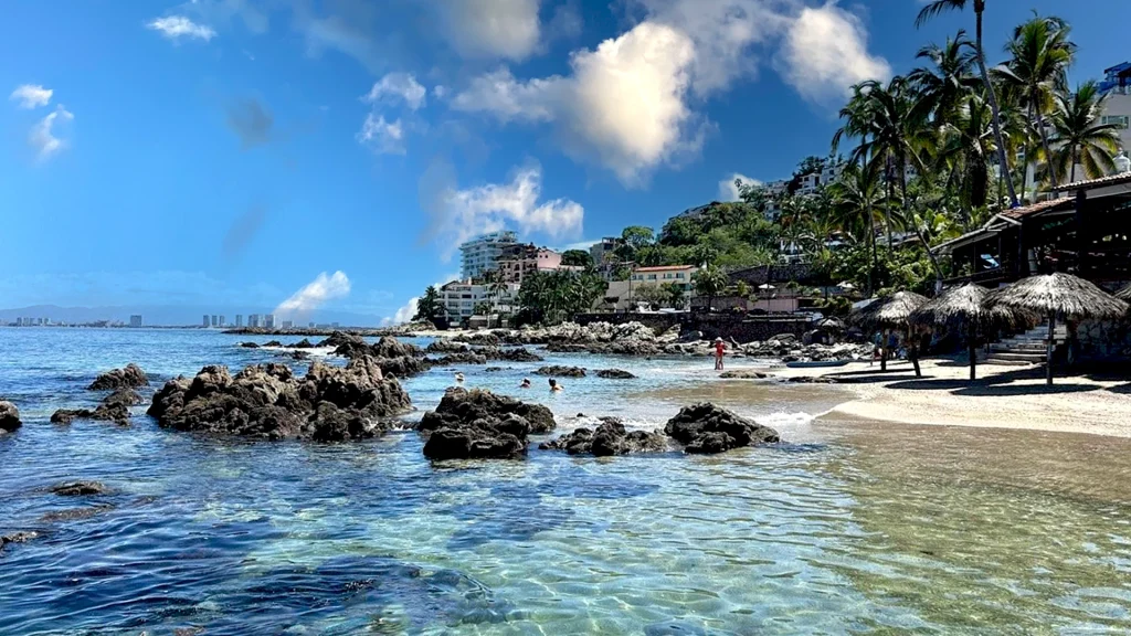 Crystal-clear water and rocky shoreline at Playa Conchas Chinas in Puerto Vallarta, Mexico.