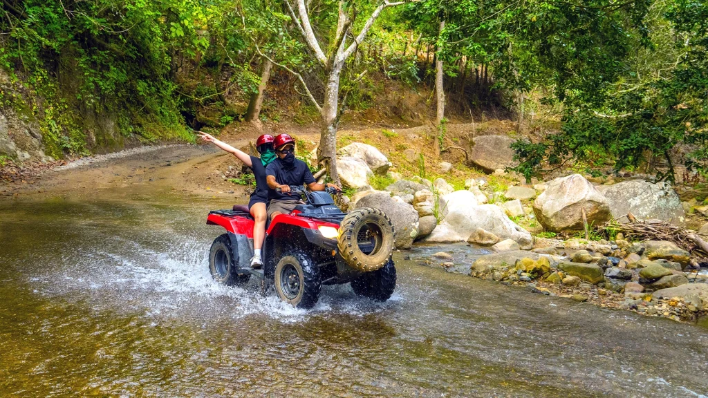 Guests riding an ATV through a river crossing on the River Park ATV and RZR Tour near Puerto Vallarta