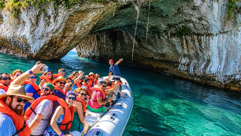 Guests in an inflatable boat exploring a coastal rock formation during the Sea Safari & Beach BBQ in Puerto Vallarta