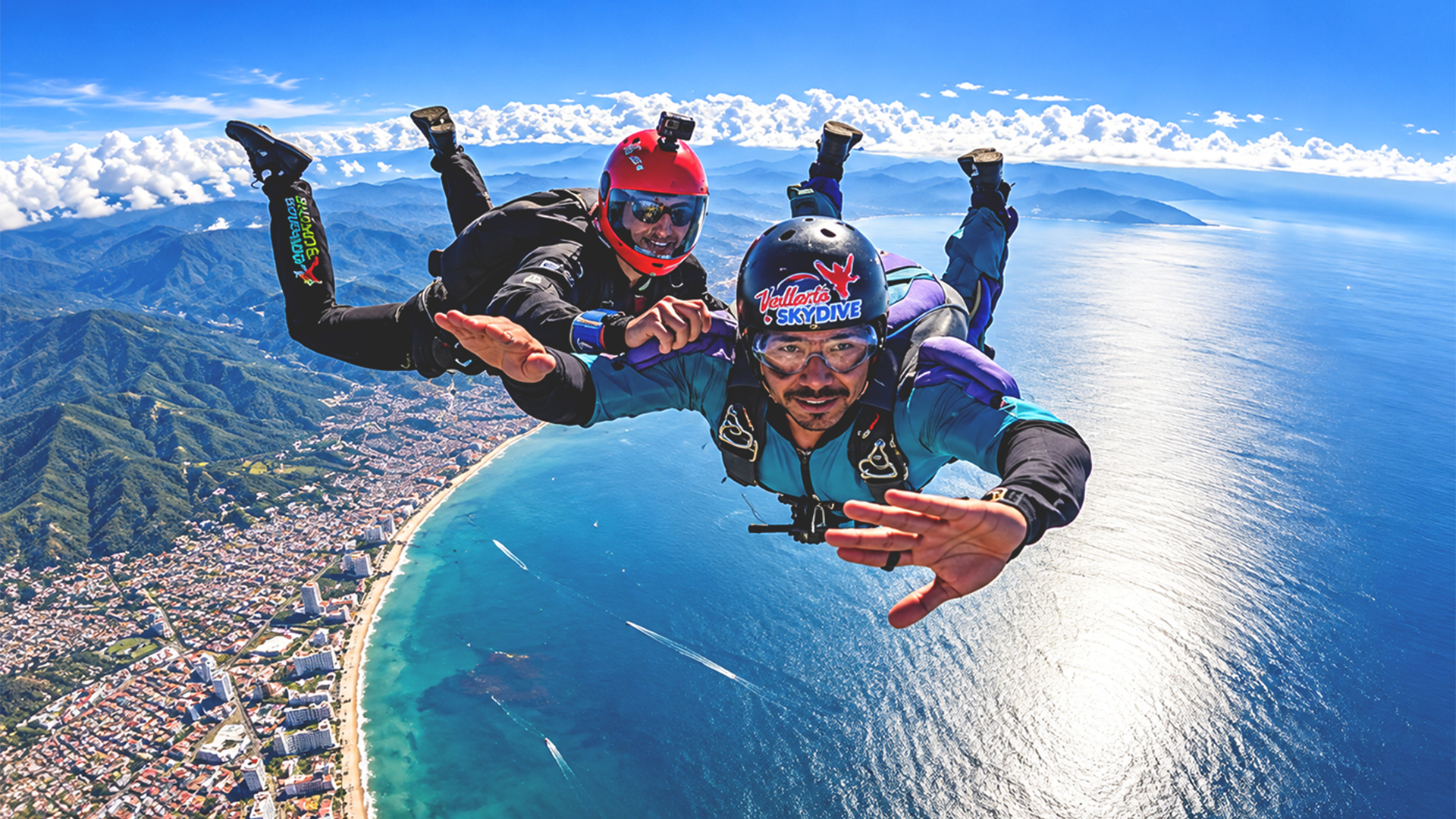 Skydivers in freefall above Puerto Vallarta with Banderas Bay and the Sierra Madre mountains below