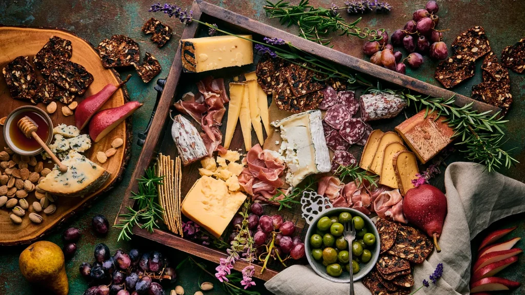 Gourmet cheese and charcuterie board with artisan cheeses, cured meats, grapes, pears, olives, nuts, honey and specialty crackers.